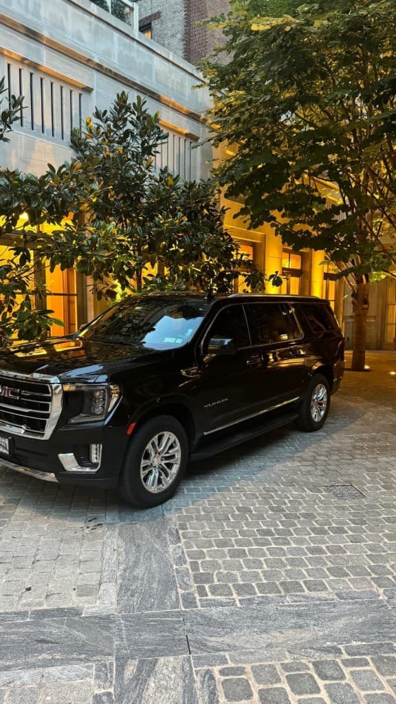 Black luxury GMC Yukon wedding limousine at an upscale venue entrance